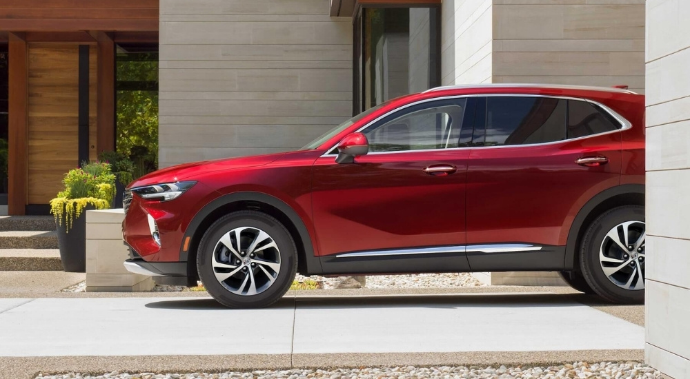 A red 2023 Buick Envision parked outside of a modern house after leaving a Buick dealer.