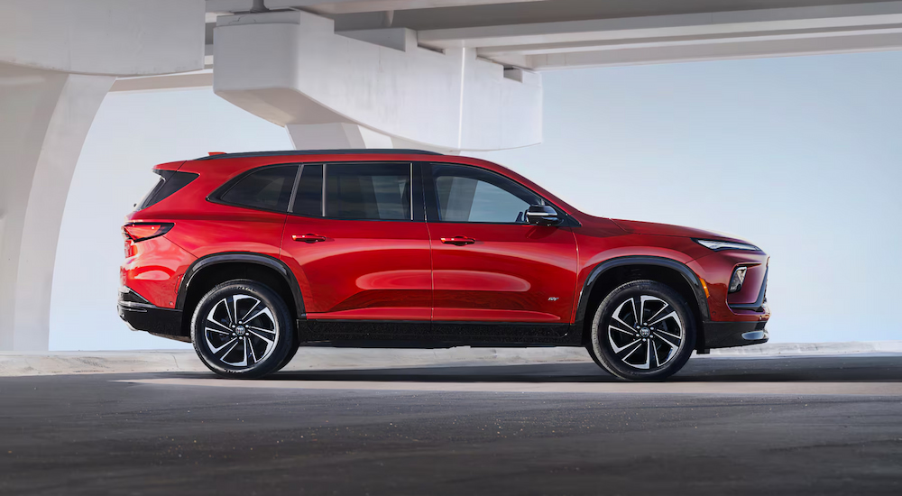 Side view of a red 2025 Buick Enclave Sport Touring parked outside a car dealer near me.