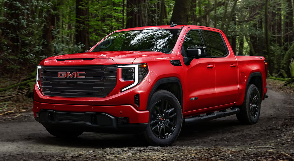 A red 2025 GMC Sierra 1500 Elevation driving on a dirt trail in the woods.