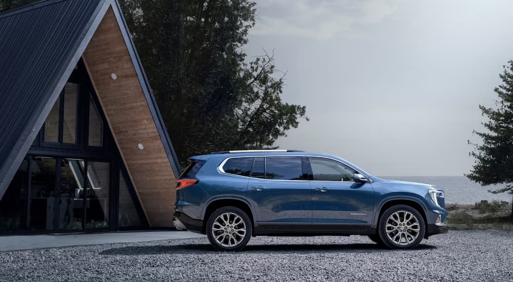 A blue 2025 GMC Acadia Denali parked next to an a-frame house.