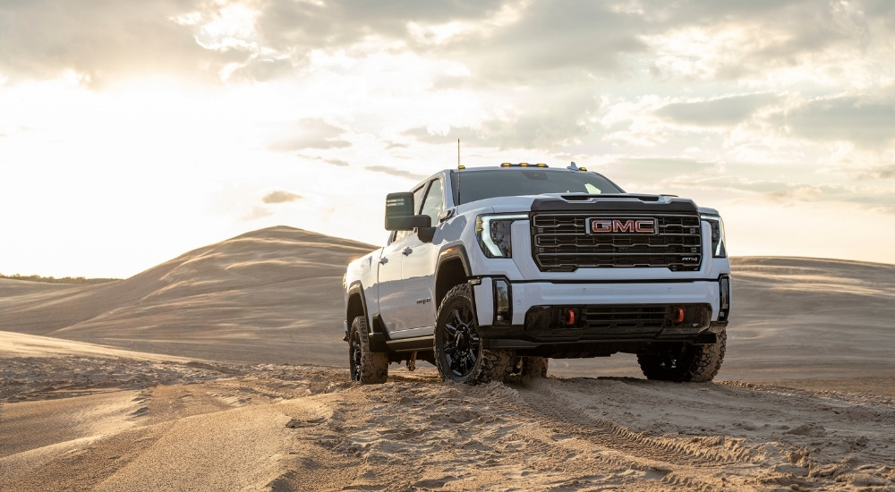 A white 2025 GMC Sierra 3500 AT4 is shown from the front at an angle.