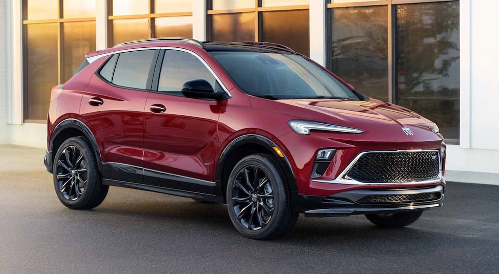A red 2025 Buick Encore GX ST for sale parked near a white building.