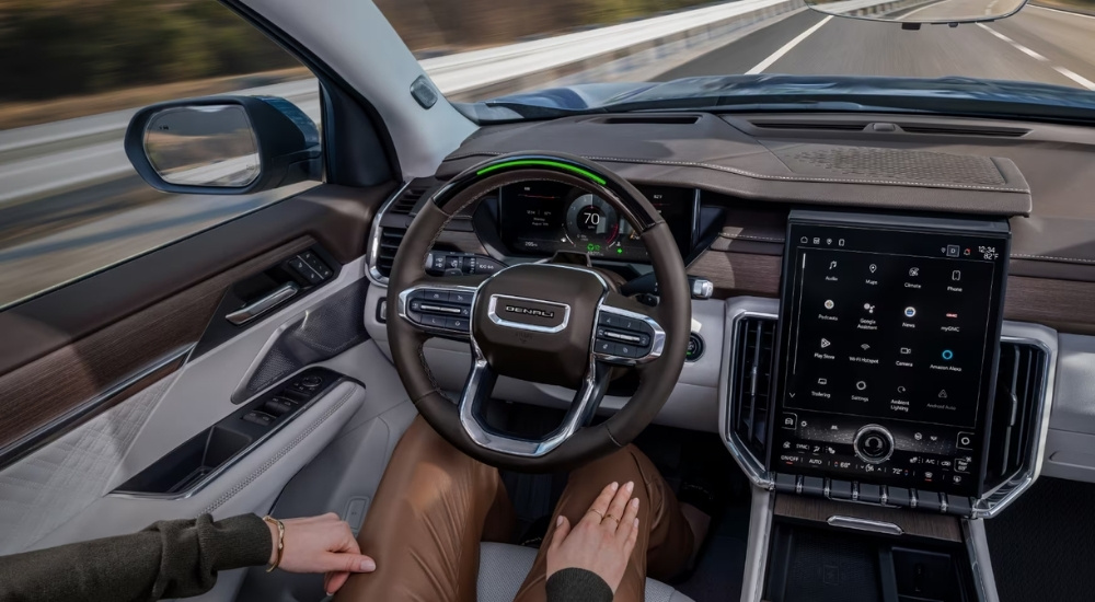 A woman using SuperCruise in a 2025 GMC Acadia AT4