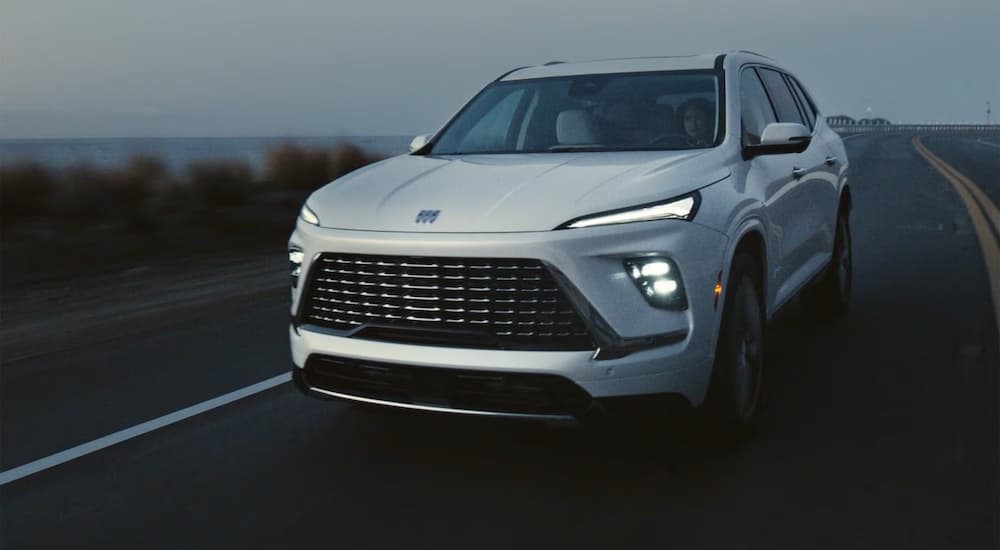 A white 2026 Buick Enclave for sale driving on a highway.