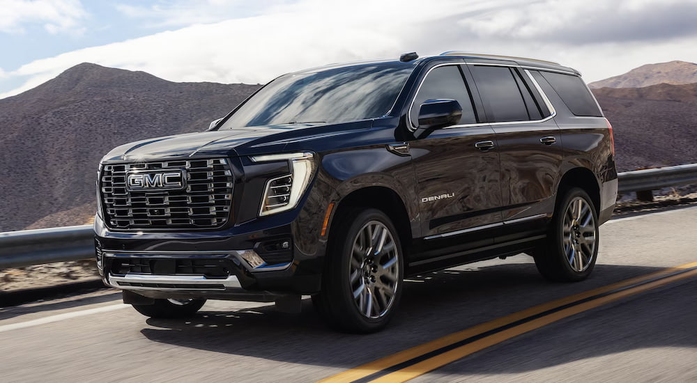 Black 2026 GMC Yukon XL Denali for sale driving down a road.