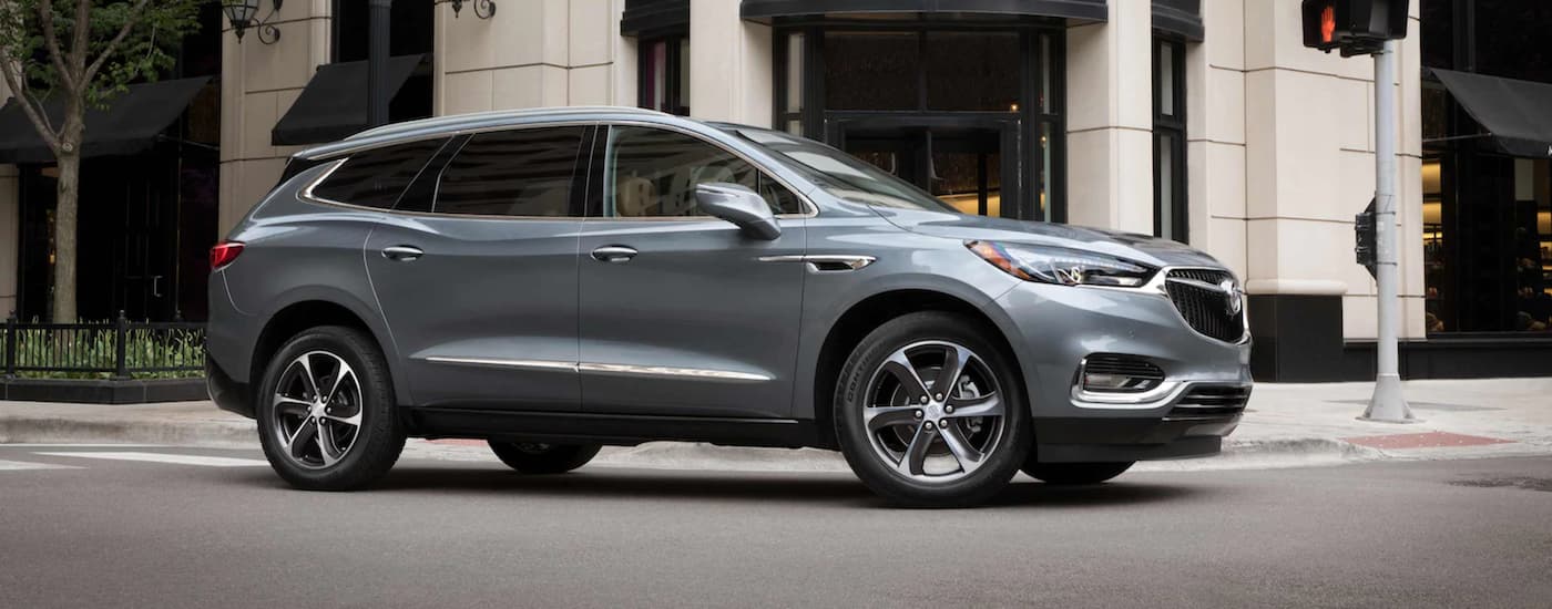 Side of a grey 2021 Buick Enclave driving in a city.