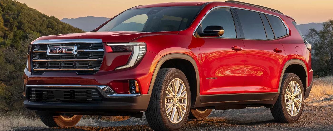 Red 2026 GMC Acadia on a dirt trail.