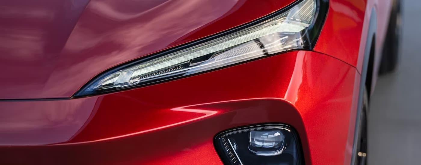 A close up of the headlight of a red 2024 Buick Envision at a Buick dealership near Minneapolis.
