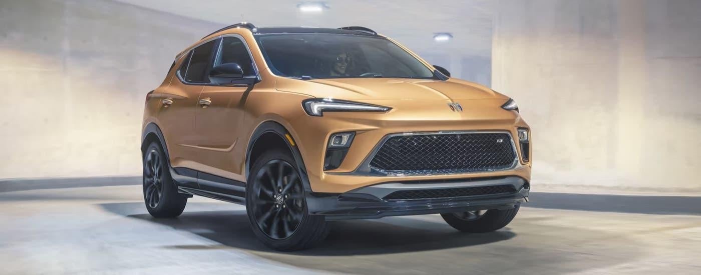 A gold 2024 Buick Encore GX driving through a parking garage.