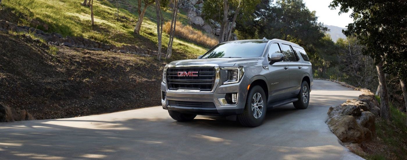 A silver 2024 GMC Yukon is parked on a winding driveway.