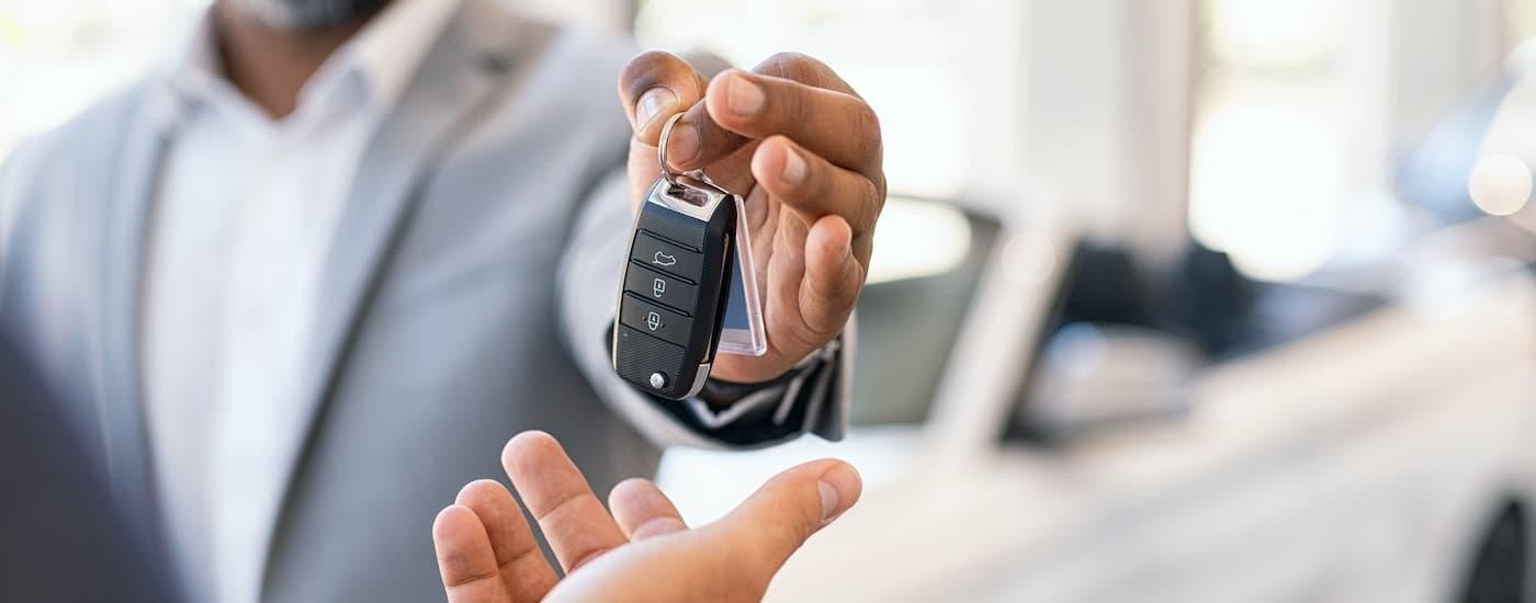 A salesman is holding up a key inside of a dealership.