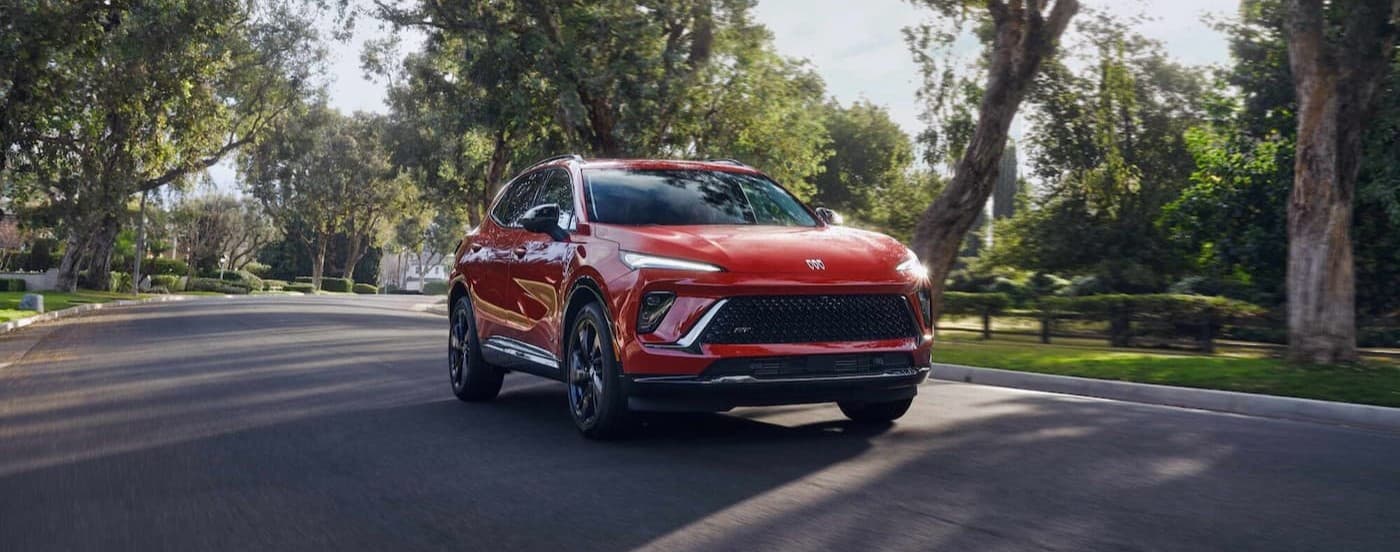 A red 2026 Buick Envision driving on a neighborhood road.