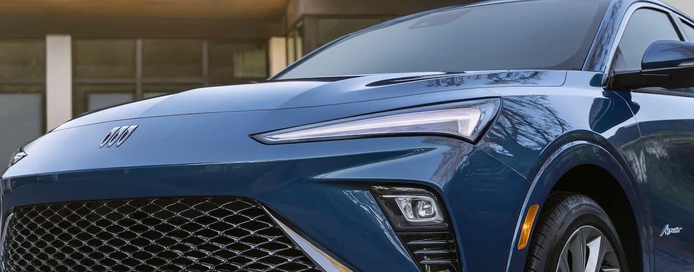 A close up of the front of a blue 2024 Buick Envista at a dealer with cars for sale.