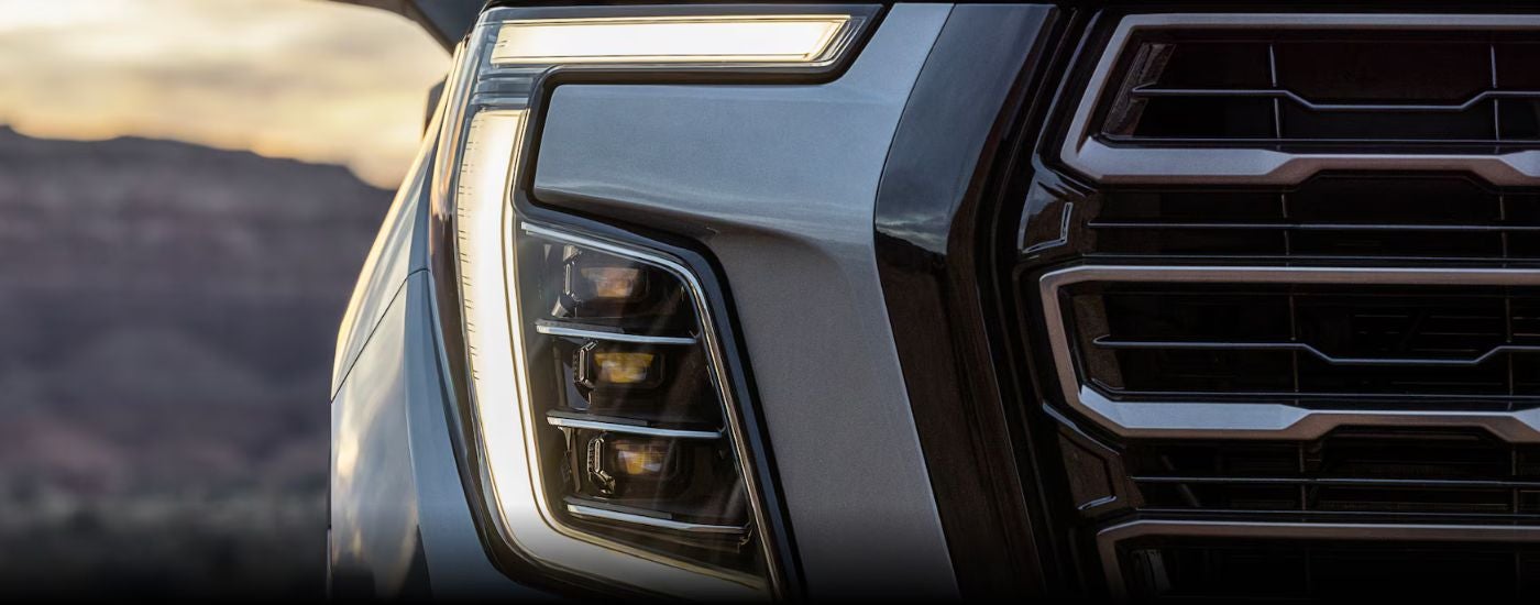 A close up of the headlight on a white 2025 GMC Yukon for sale at a GMC dealer near Le Sueur.