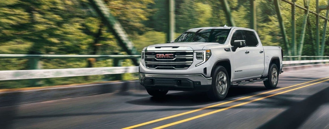 A white 2024 GMC Sierra 1500 SLE driving across a bridge after visiting a GMC dealer near Owatonna.