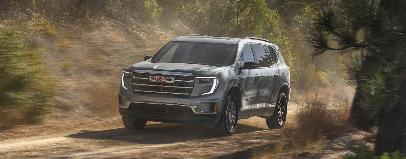 A grey 2025 GMC Acadia is shown driving off-road.