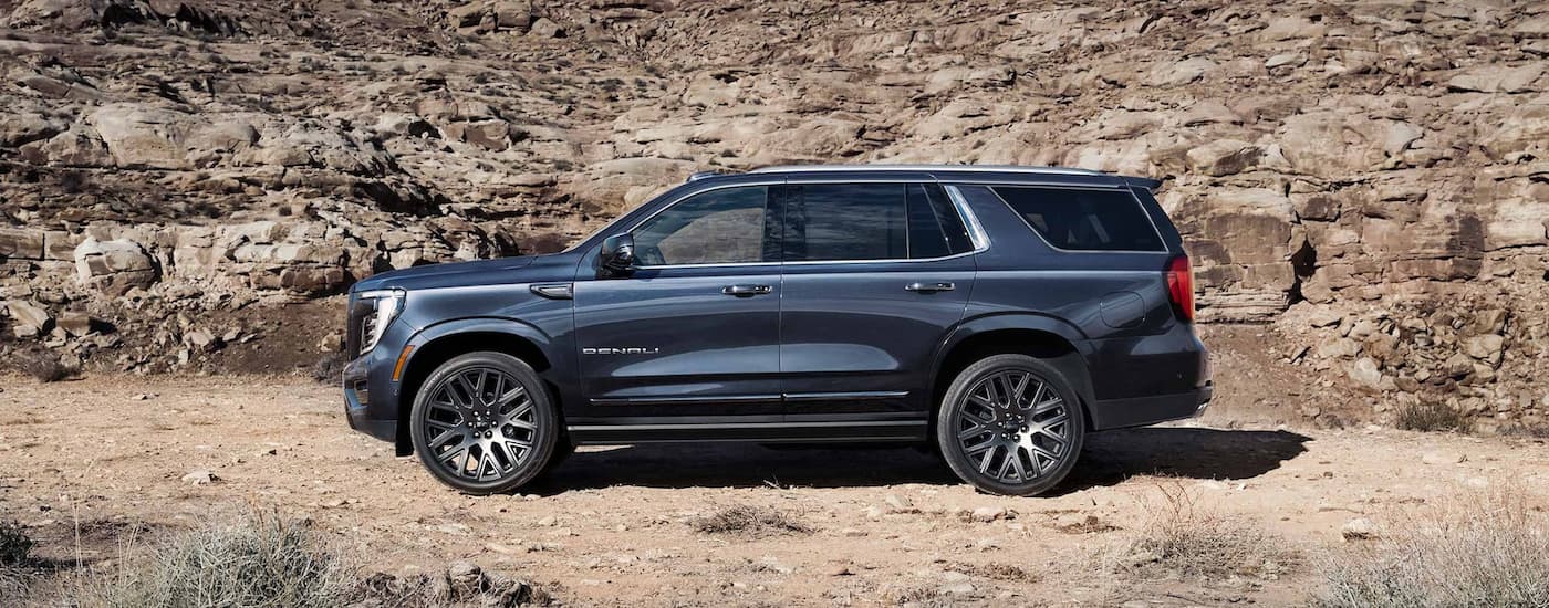 Side of a dark blue 2026 GMC Yukon XL parked off-road.