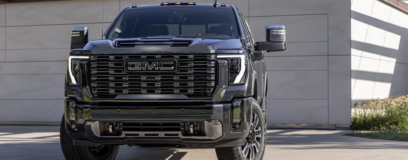 A black 2024 GMC Sierra 2500 HD Denali Ultimate is parked in a driveway.