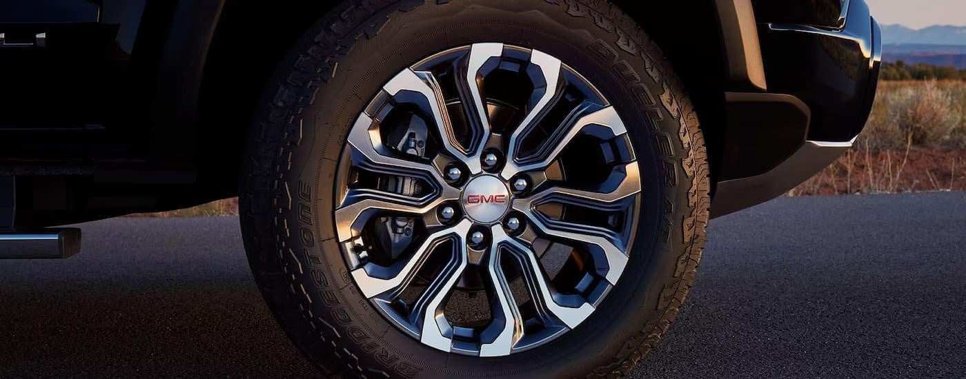 A close up of the tire on a black 2024 GMC Canyon at a dealer with trucks for sale near Minneapolis.