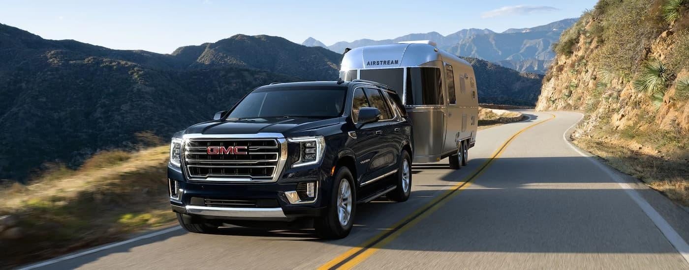 A 2022 GMC Yukon is shown towing an Airstream camper trailer on an open highway.