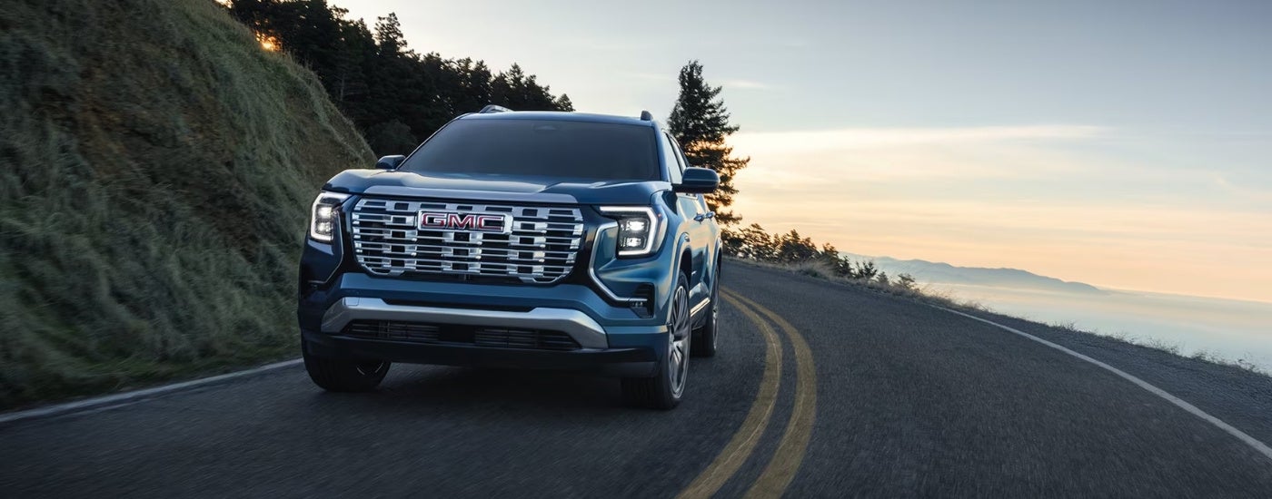 A blue 2026 GMC Terrain Denali driving on a highway