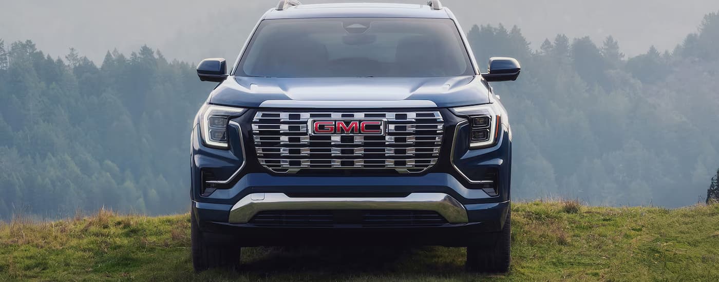 A blue 2026 GMC Terrain Denali pstked off-road on grass